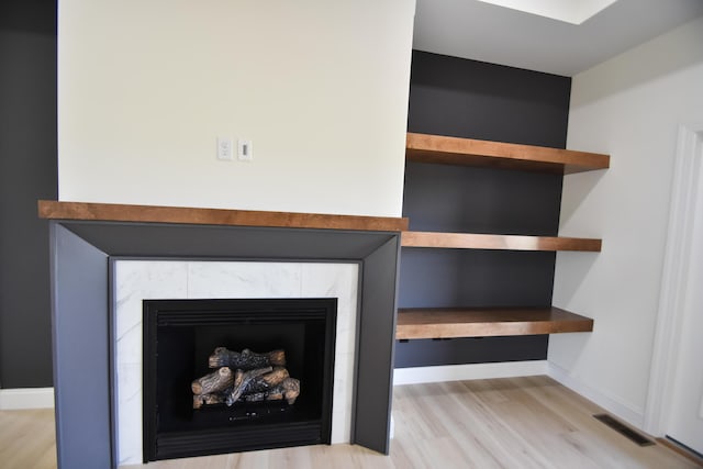 detailed view of wood finished floors, a tile fireplace, and baseboards