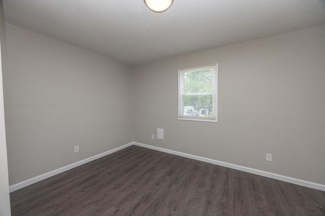 unfurnished room with dark wood finished floors and baseboards