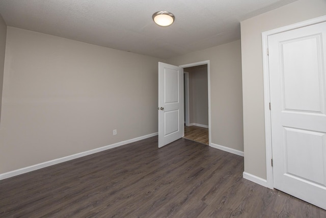 unfurnished bedroom with dark wood-style floors and baseboards