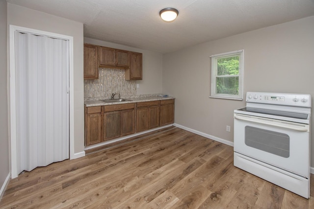 kitchen with electric range, light countertops, brown cabinets, and light wood-type flooring