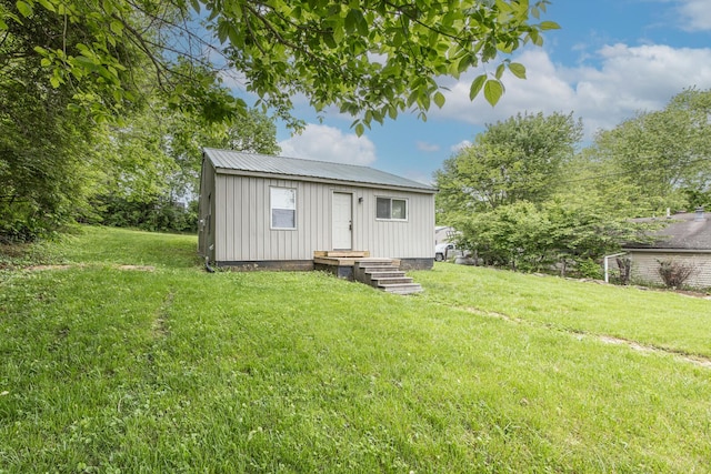back of property with board and batten siding, a yard, and metal roof