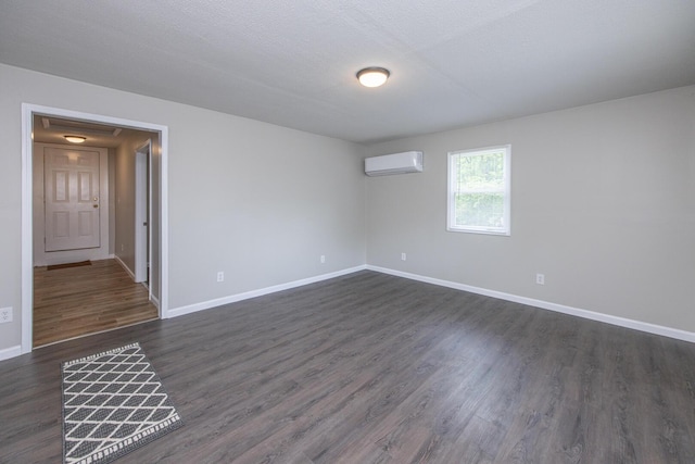unfurnished room featuring a wall mounted AC, baseboards, and dark wood-style floors