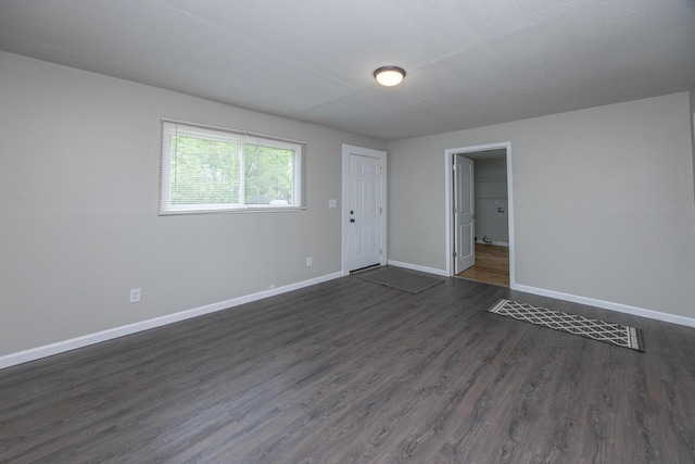unfurnished room featuring baseboards and dark wood-type flooring