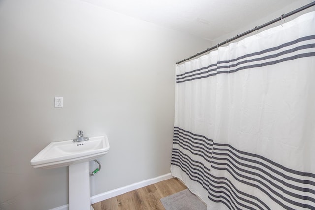 full bath featuring wood finished floors, baseboards, and a shower with shower curtain