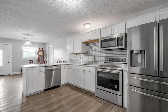 524 Joel St, Lexington, KY 40508 - kitchen featuring stainless steel appliances, a textured ceiling, a peninsula, white cabinets, and tasteful backsplash