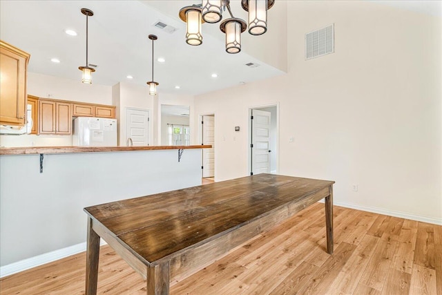 kitchen featuring freestanding refrigerator, light wood-style flooring, a breakfast bar, a chandelier, and recessed lighting
