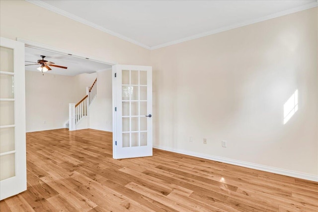 spare room featuring french doors, light wood-style flooring, crown molding, stairs, and baseboards