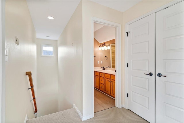 hallway featuring light tile patterned floors, baseboards, and an upstairs landing