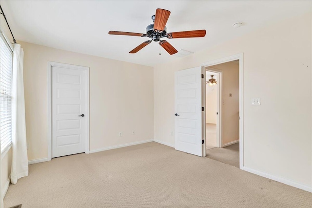 unfurnished bedroom featuring light carpet, multiple windows, baseboards, and ceiling fan