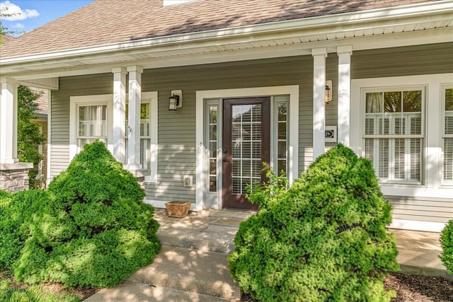 doorway to property with roof with shingles and a porch