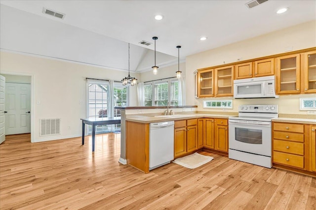 kitchen featuring white appliances, vaulted ceiling, light wood-style flooring, a peninsula, and decorative light fixtures