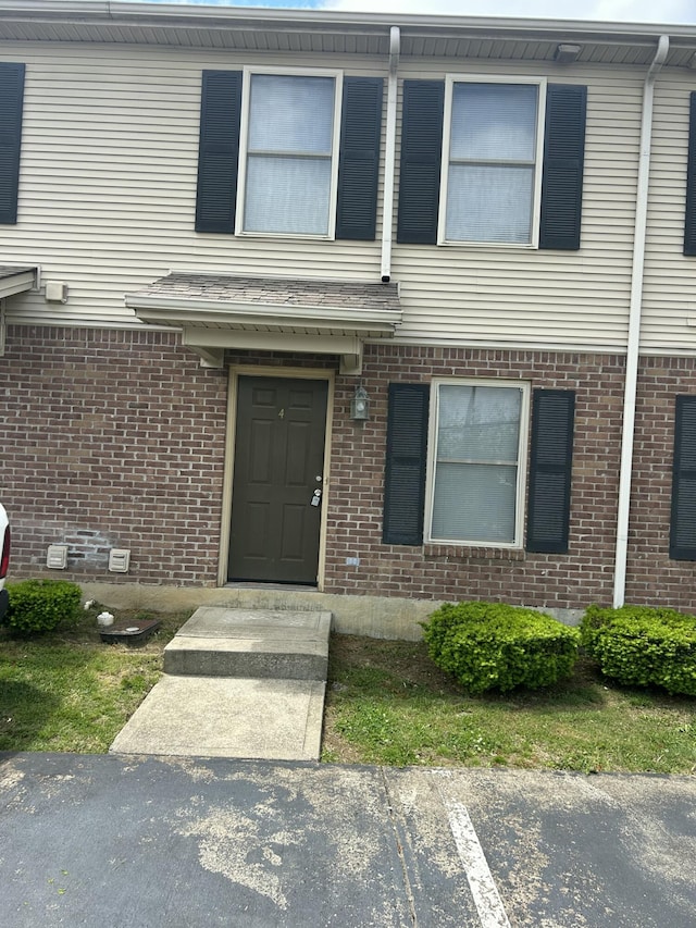 view of exterior entry featuring brick siding and uncovered parking