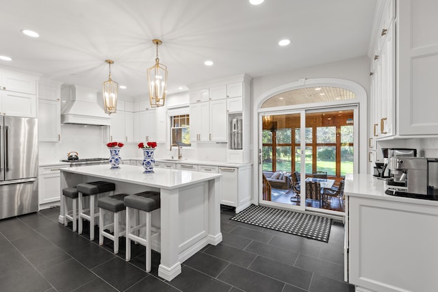 kitchen with custom range hood, appliances with stainless steel finishes, white cabinets, dark tile patterned flooring, and light countertops