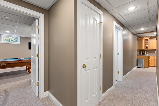 corridor with light carpet, baseboards, a drop ceiling, and recessed lighting