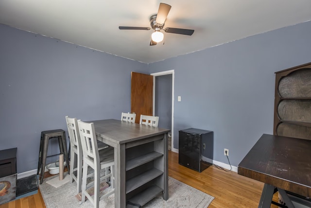 dining space with a ceiling fan, wood finished floors, baseboards, and a desk