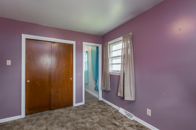 unfurnished bedroom featuring baseboards, carpet flooring, and a closet