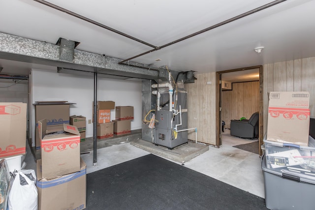 basement featuring wooden walls and heating unit