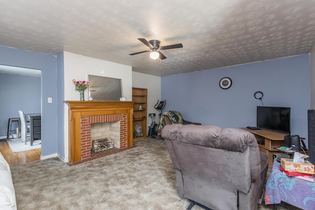 carpeted living room featuring a textured ceiling, a ceiling fan, a brick fireplace, and baseboards