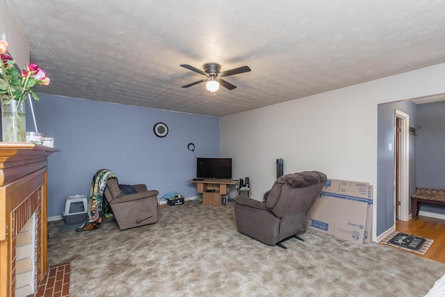 living room featuring ceiling fan, a textured ceiling, baseboards, and carpet flooring