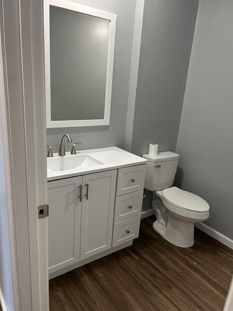 bathroom featuring wood finished floors, vanity, baseboards, and toilet