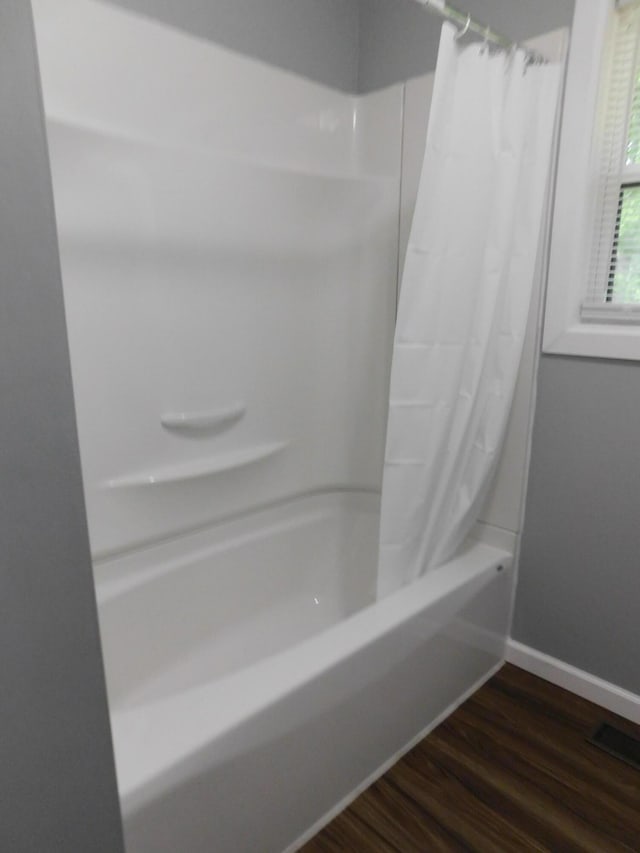 full bathroom featuring baseboards, wood finished floors, and shower / bath combination with curtain