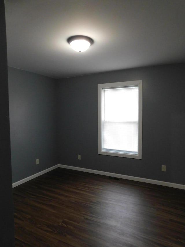 empty room featuring dark wood-style floors and baseboards