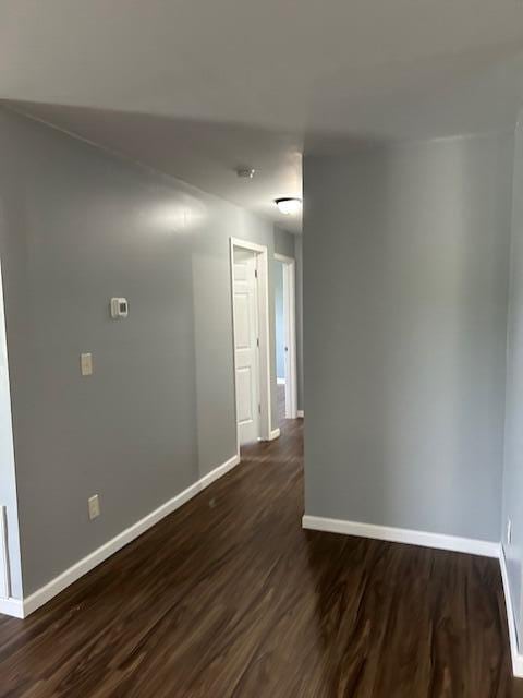 unfurnished room with baseboards and dark wood-style floors