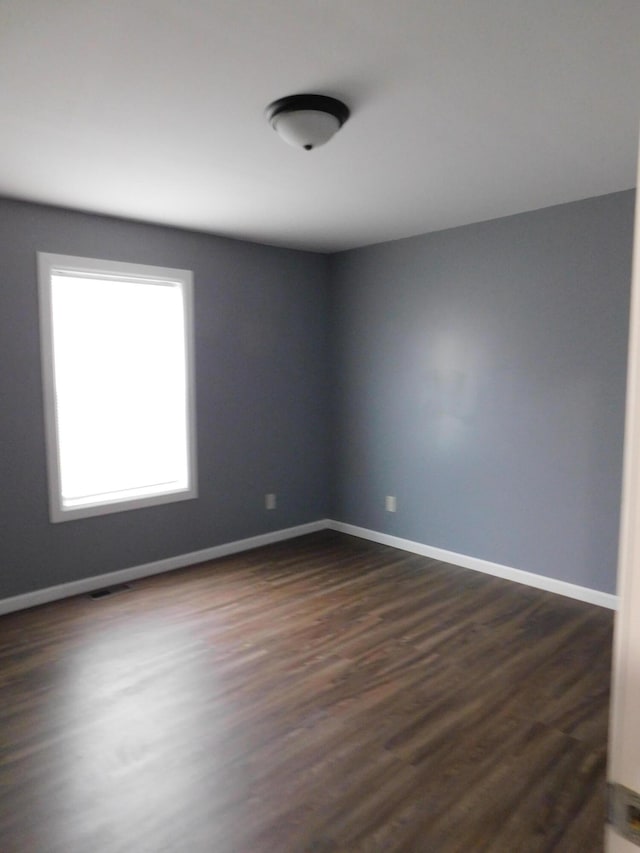 empty room with dark wood-style floors and baseboards