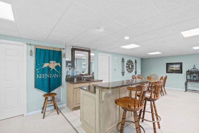 2221 Broadhead Pl, Lexington, KY 40515 - kitchen with a breakfast bar, light colored carpet, a drop ceiling, dark stone countertops, and baseboards