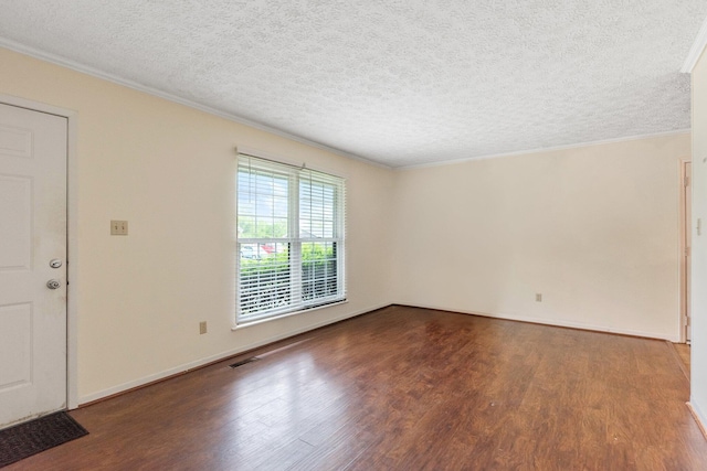 empty room with wood finished floors, a textured ceiling, and crown molding