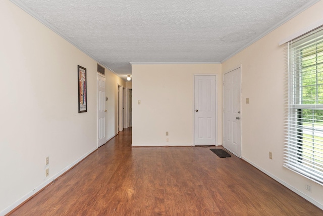 spare room with wood finished floors, ornamental molding, a textured ceiling, and baseboards