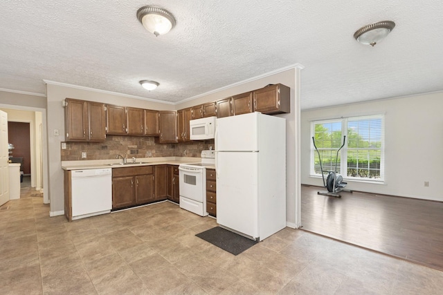 kitchen with white appliances, light countertops, a sink, crown molding, and backsplash