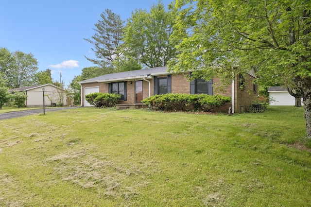 view of front facade with an attached garage, brick siding, a front yard, metal roof, and driveway