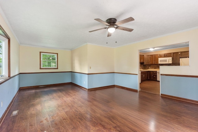 spare room featuring dark wood-type flooring, a ceiling fan, baseboards, and crown molding