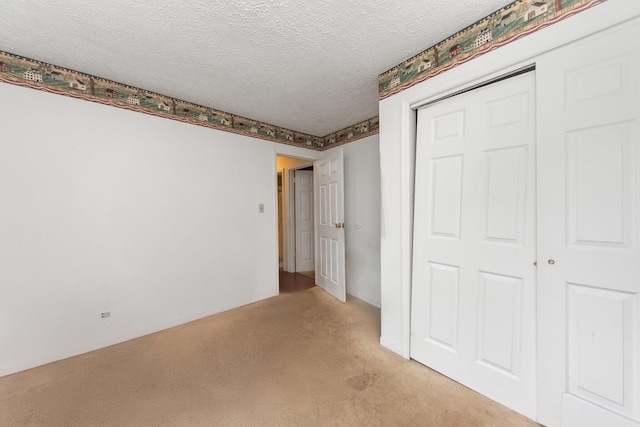 unfurnished bedroom with light colored carpet, a textured ceiling, and a closet