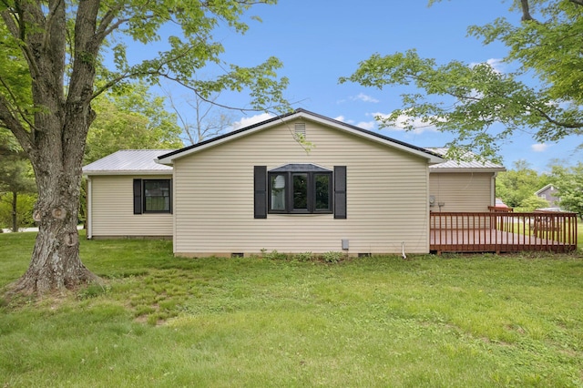 view of side of property featuring crawl space, a deck, metal roof, and a lawn