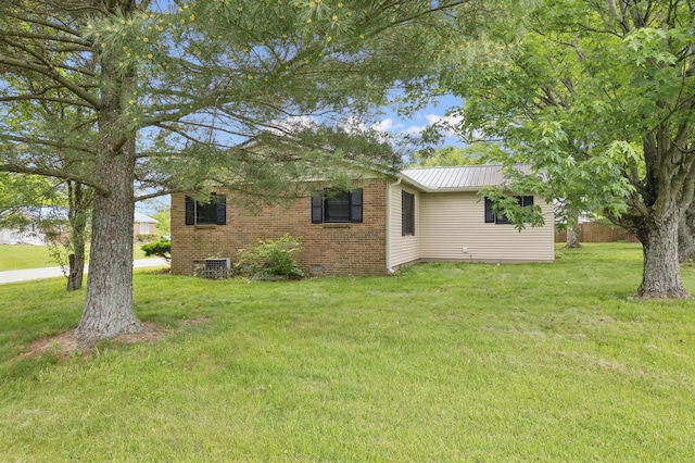 back of house featuring a yard, metal roof, and brick siding