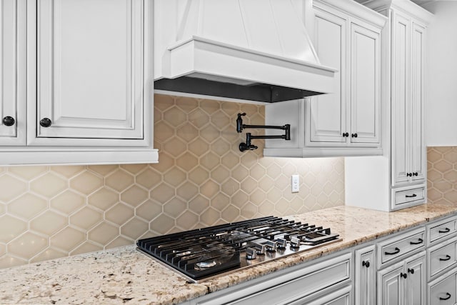 6031 Old S Dr, Richmond, KY 40475 - kitchen with custom range hood, stainless steel gas cooktop, backsplash, white cabinetry, and light stone countertops