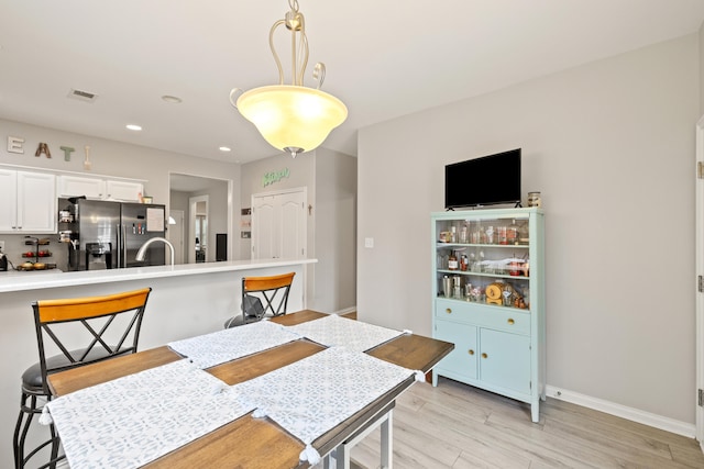 dining space featuring light wood-style floors, baseboards, and recessed lighting