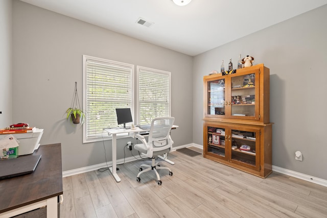 home office with light wood-style flooring and baseboards