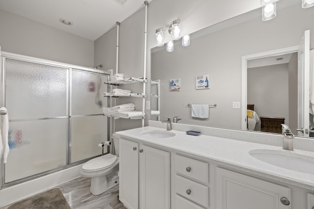 bathroom featuring ensuite bathroom, a shower stall, toilet, and double vanity