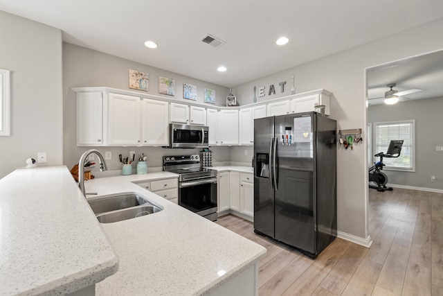 kitchen featuring appliances with stainless steel finishes, a sink, white cabinets, light wood-style floors, and recessed lighting