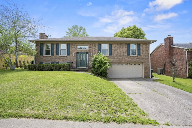 raised ranch featuring a garage, a chimney, driveway, brick siding, and central air condition unit