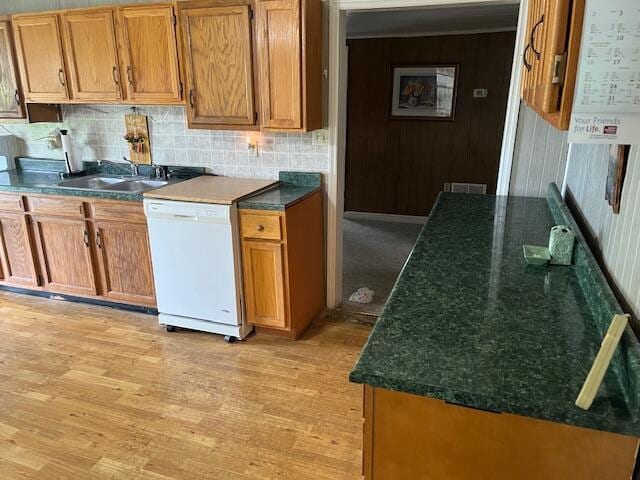 kitchen with dishwasher, a sink, light wood-style floors, and decorative backsplash