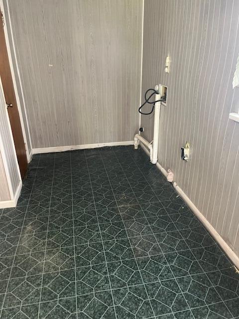 interior space featuring washer hookup, dark flooring, and baseboards