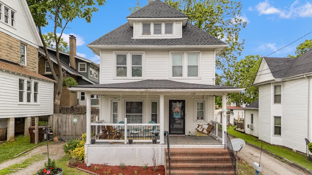 traditional style home with a porch and roof with shingles