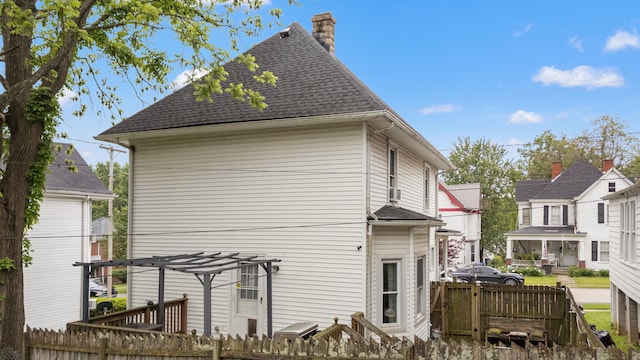 view of side of property featuring a chimney, a pergola, fence, and roof with shingles