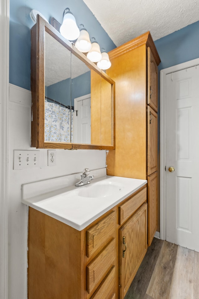 full bathroom with wood finished floors, vanity, and a textured ceiling
