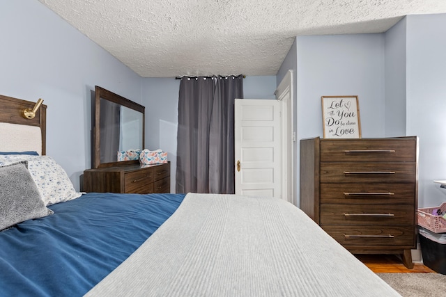 bedroom with a textured ceiling and wood finished floors