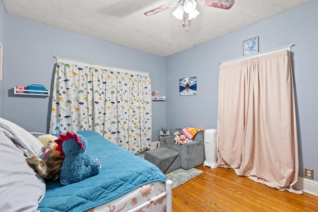 bedroom featuring wood finished floors, a textured ceiling, ceiling fan, and baseboards